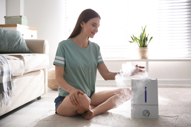 Woman near modern air humidifier at home