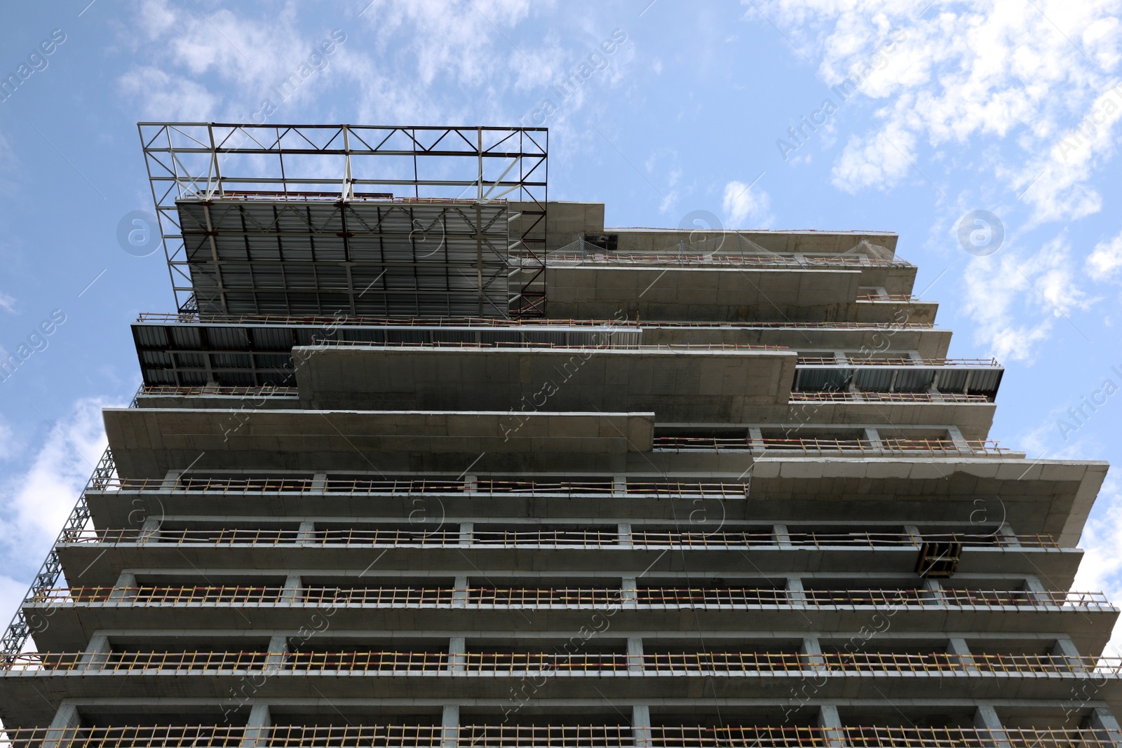 Photo of Multistory building under construction against cloudy sky, low angle view