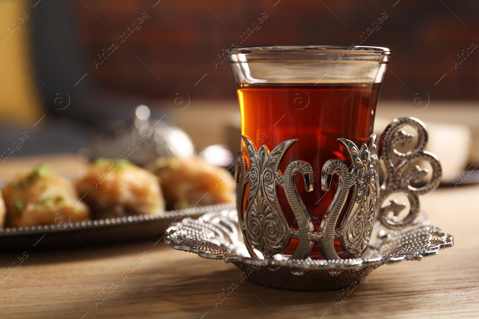 Photo of Glass of traditional Turkish tea in vintage holder on wooden table, closeup. Space for text