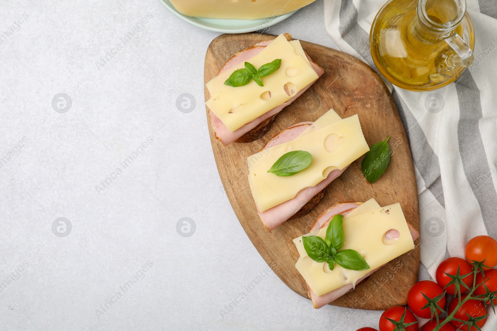 Photo of Delicious sandwiches with ham, cheese and products on light table, flat lay. Space for text