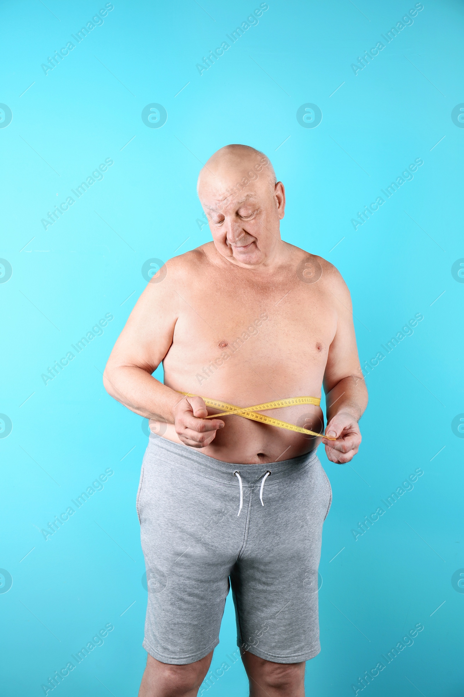 Photo of Fat senior man with measuring tape on color background. Weight loss