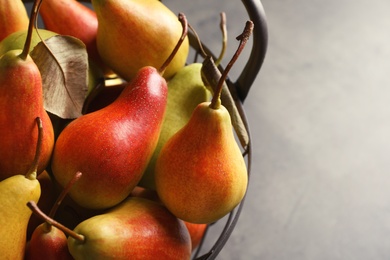 Basket with ripe pears on grey background, closeup. Space for text