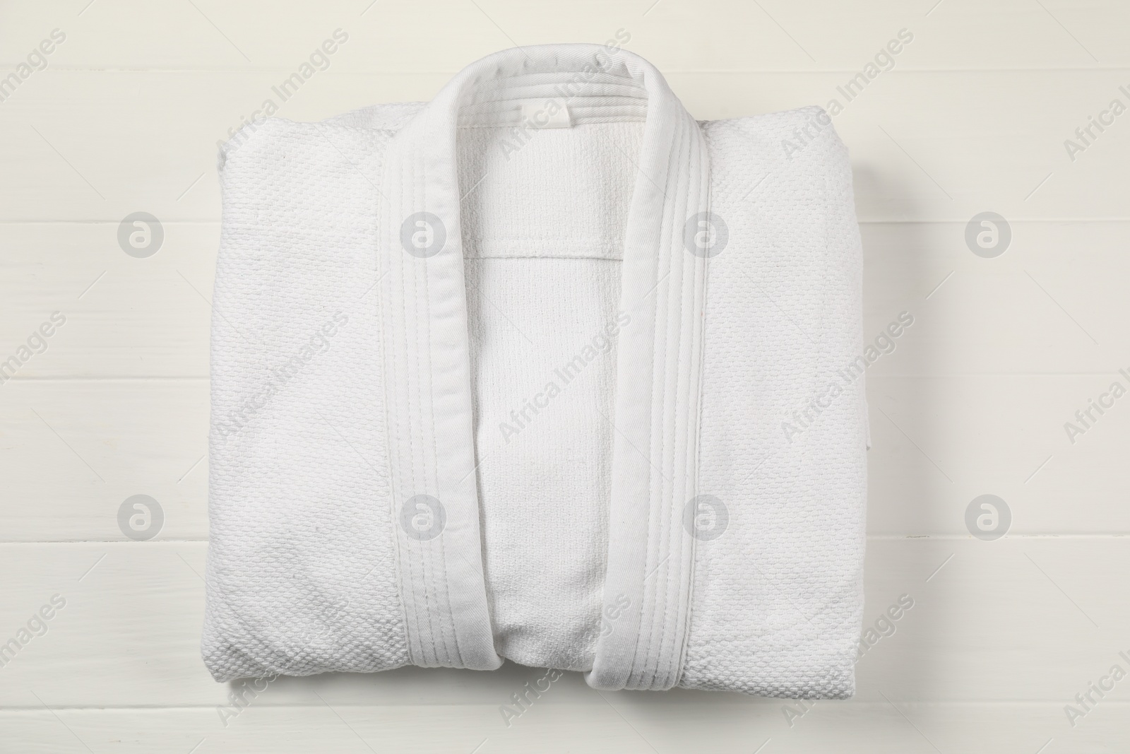 Photo of White kimono on wooden background, top view