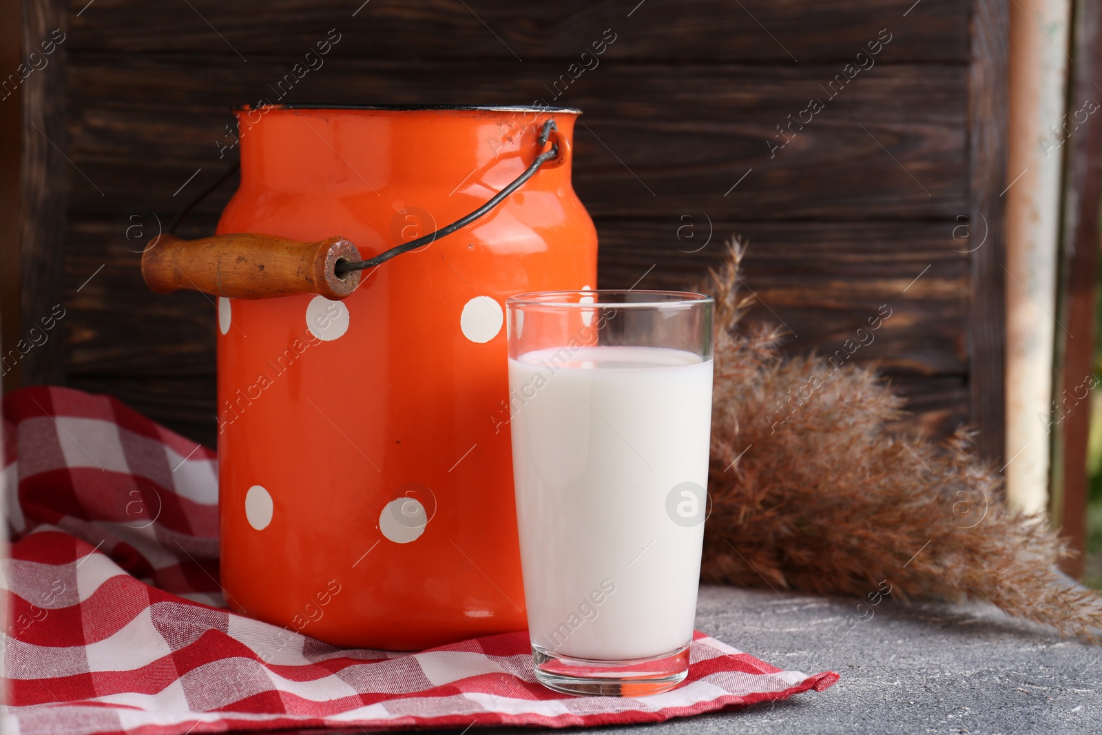 Photo of Can and glass of fresh milk on grey table. Space for text