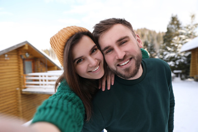 Photo of Young couple taking selfie on snowy day. Winter vacation