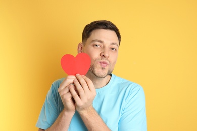 Photo of Portrait of man with paper heart on color background