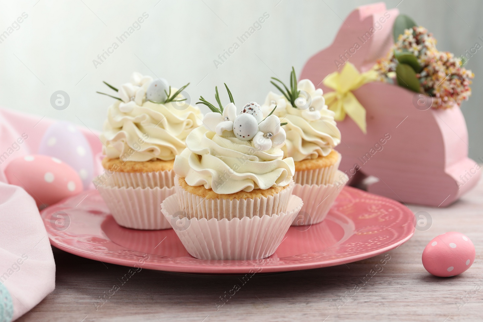 Photo of Tasty Easter cupcakes with vanilla cream on wooden table