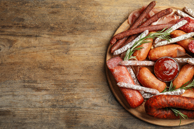 Photo of Different types of sausages with rosemary served on wooden table, top view. Space for text