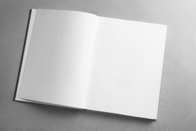 Photo of Open book on grey table, top view. Space for text