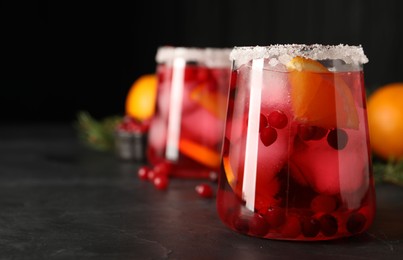 Photo of Tasty cranberry cocktail with ice cubes in glass on dark gray table, closeup. Space for text