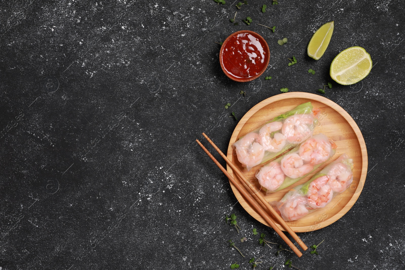 Photo of Tasty spring rolls, chopsticks, sauce, sliced lime and microgreens on grey textured table, flat lay. Space for text