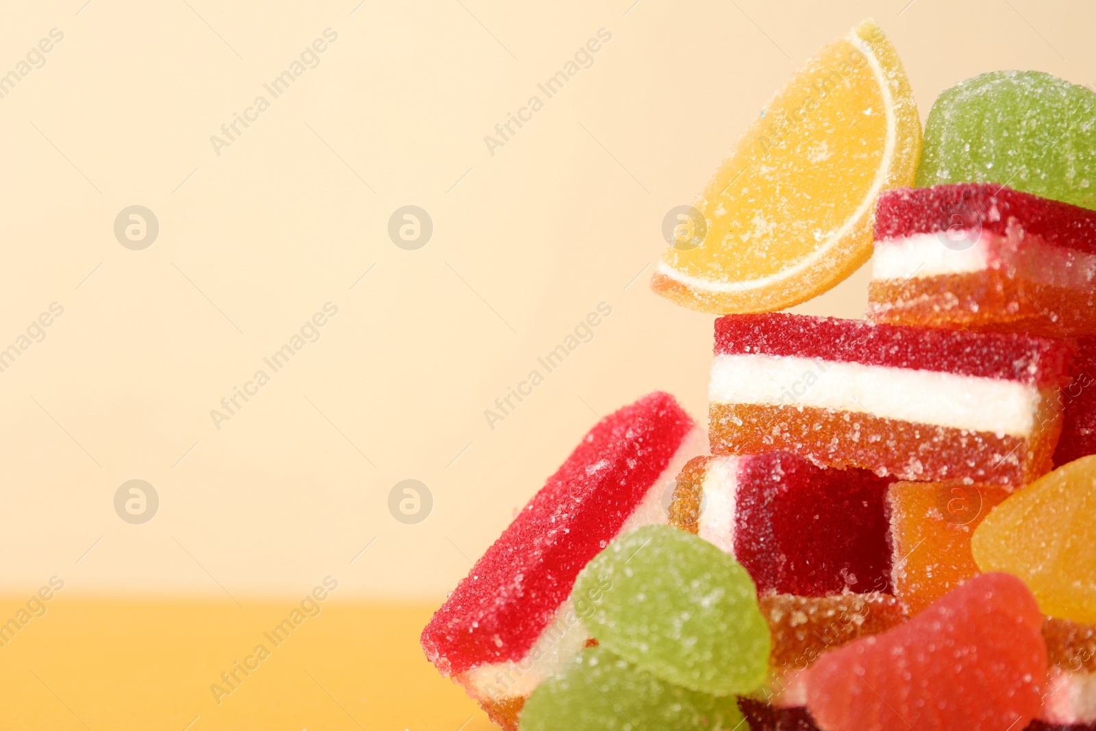 Photo of Pile of delicious bright jelly candies on yellow background, closeup. Space for text