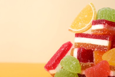 Pile of delicious bright jelly candies on yellow background, closeup. Space for text