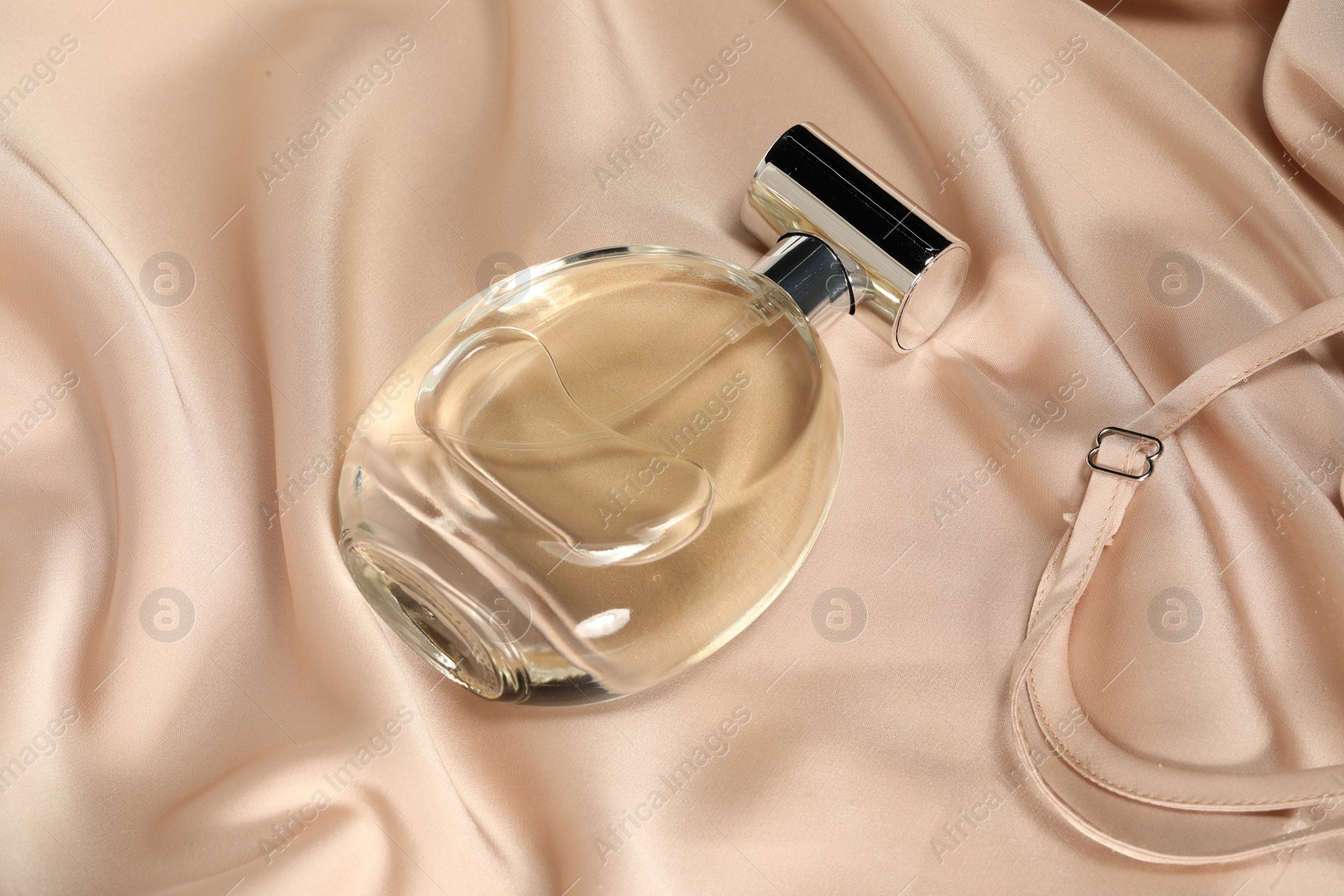 Photo of Luxury perfume in bottle on beige silk fabric