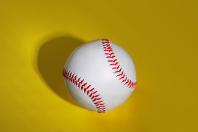 Photo of One baseball ball on yellow background, top view