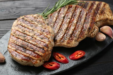 Photo of Delicious grilled pork steaks with spices on wooden table, closeup