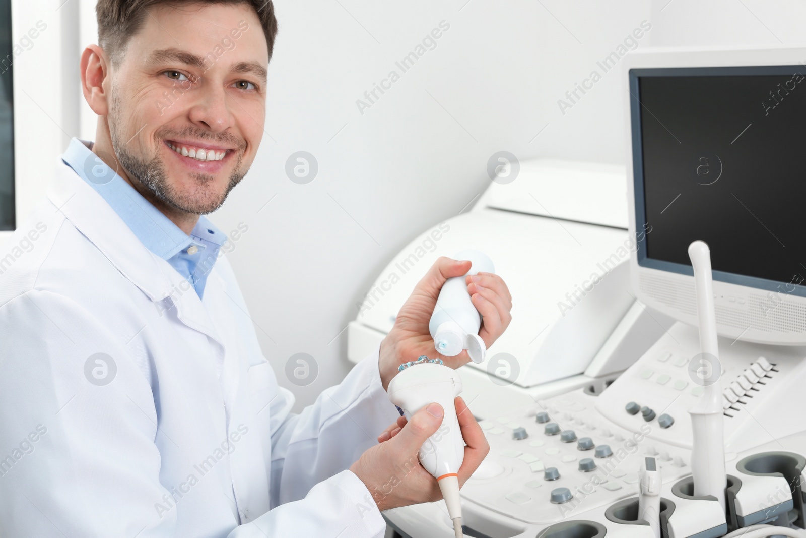 Photo of Sonographer covering ultrasound machine probe with gel in clinic