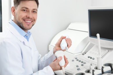 Photo of Sonographer covering ultrasound machine probe with gel in clinic