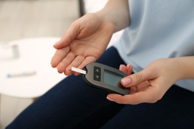 Photo of Diabetes. Woman checking blood sugar level with glucometer at home, closeup