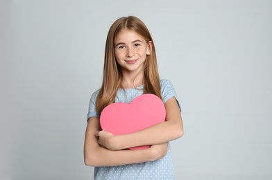 Pretty teenage girl with decorative heart on color background. Space for text