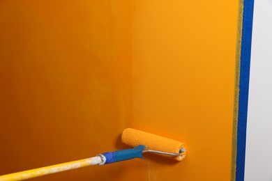 Photo of Painting wall with roller and orange dye