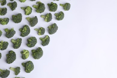 Many fresh green broccoli pieces on white background, flat lay. Space for text