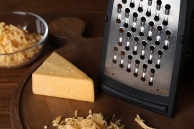 Grater and delicious cheese on wooden board, closeup