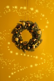 Photo of Beautiful Christmas wreath with bows, balls and cones hanging near wall, closeup