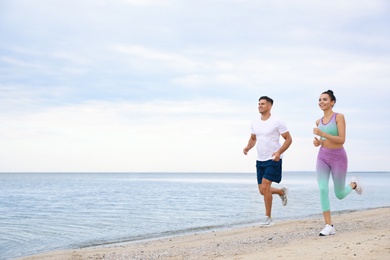 Photo of Couple running together on beach, space for text. Body training