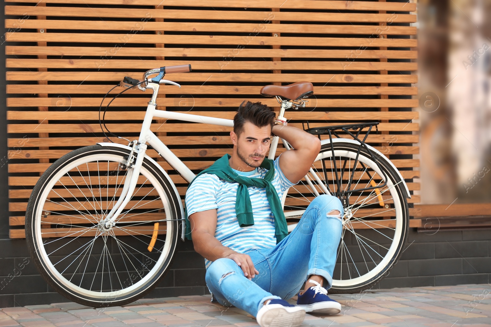 Photo of Handsome young hipster man with bicycle near wooden wall outdoors