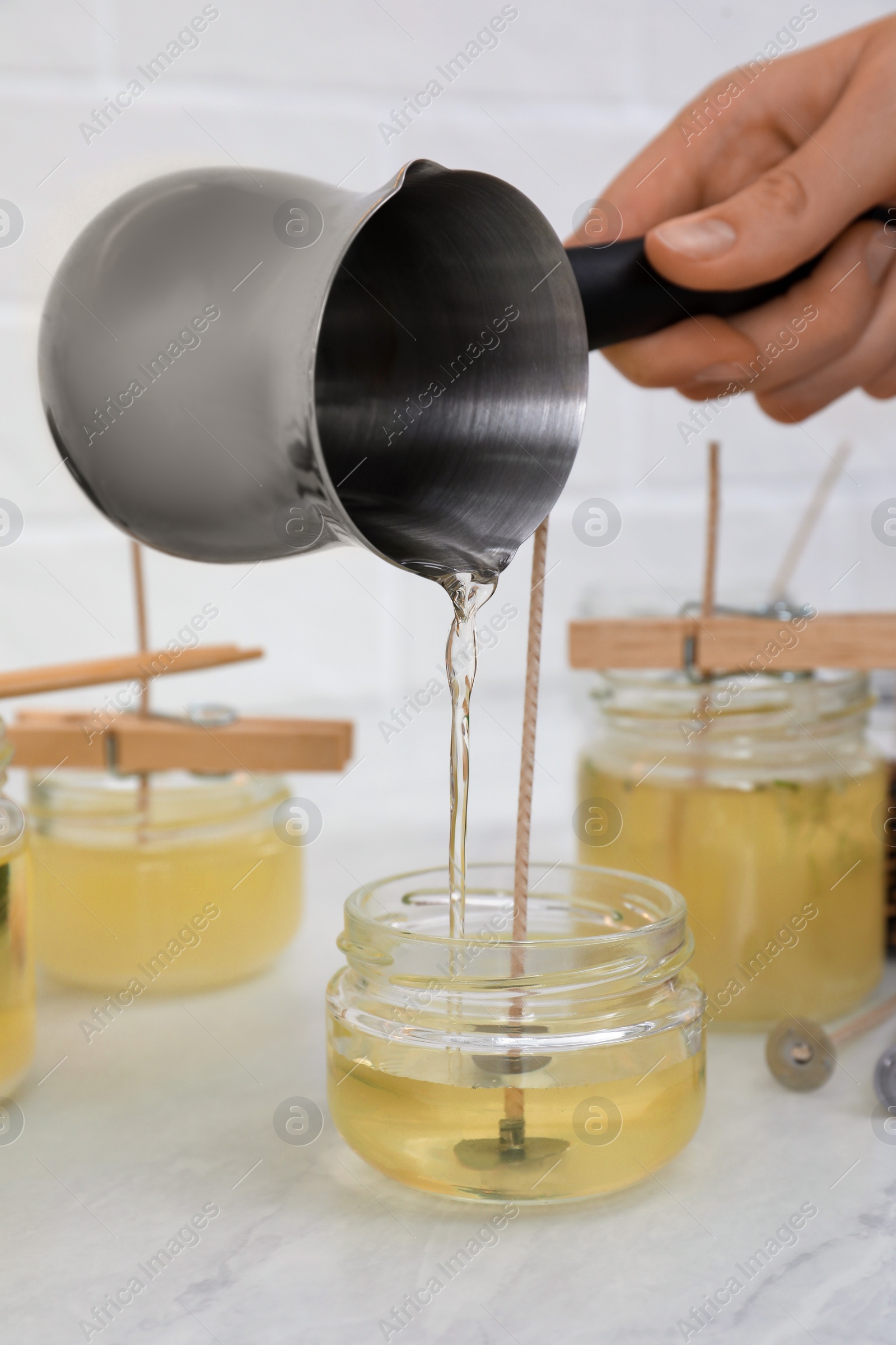 Photo of Woman making candles at white table, closeup