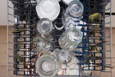 Photo of Open modern dishwasher with dirty tableware in kitchen, top view