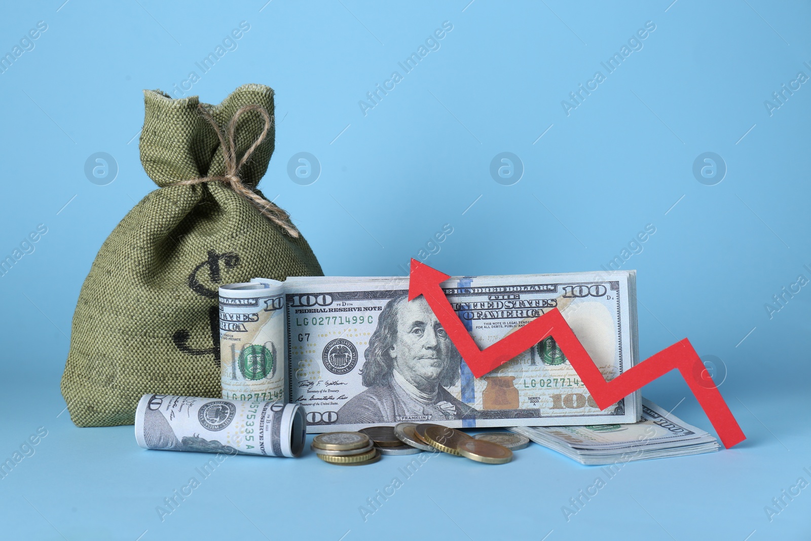 Photo of Economic profit. Money bag, coins, banknotes and arrow on light blue background