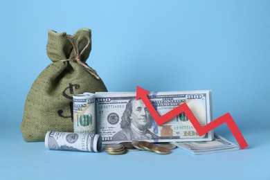 Photo of Economic profit. Money bag, coins, banknotes and arrow on light blue background