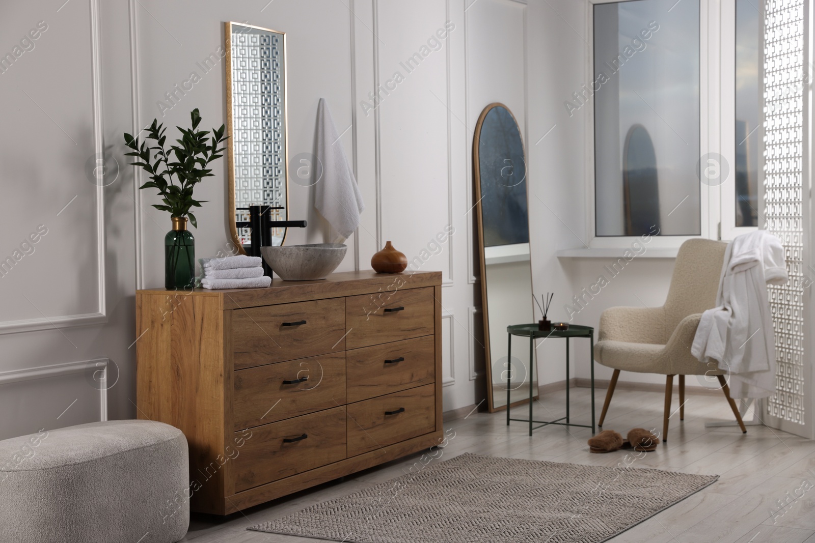 Photo of Modern bathroom interior with stylish mirror, eucalyptus branches, vessel sink and wooden vanity