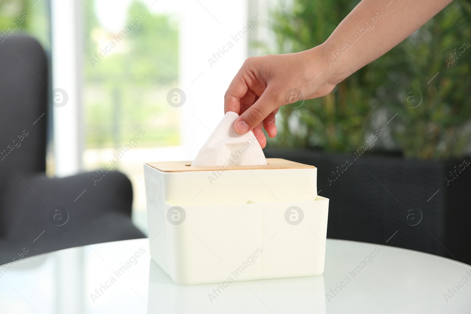 Photo of Woman taking paper tissue out of box on white table at home, closeup