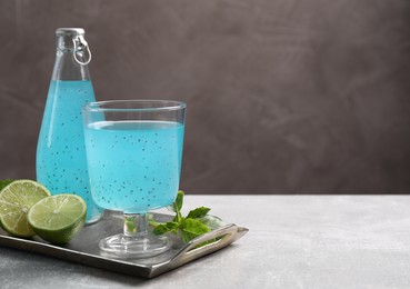 Photo of Tasty light blue drink with basil seeds on grey table, space for text