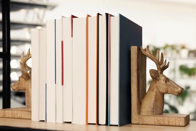 Wooden deer shaped bookends with books on shelf indoors