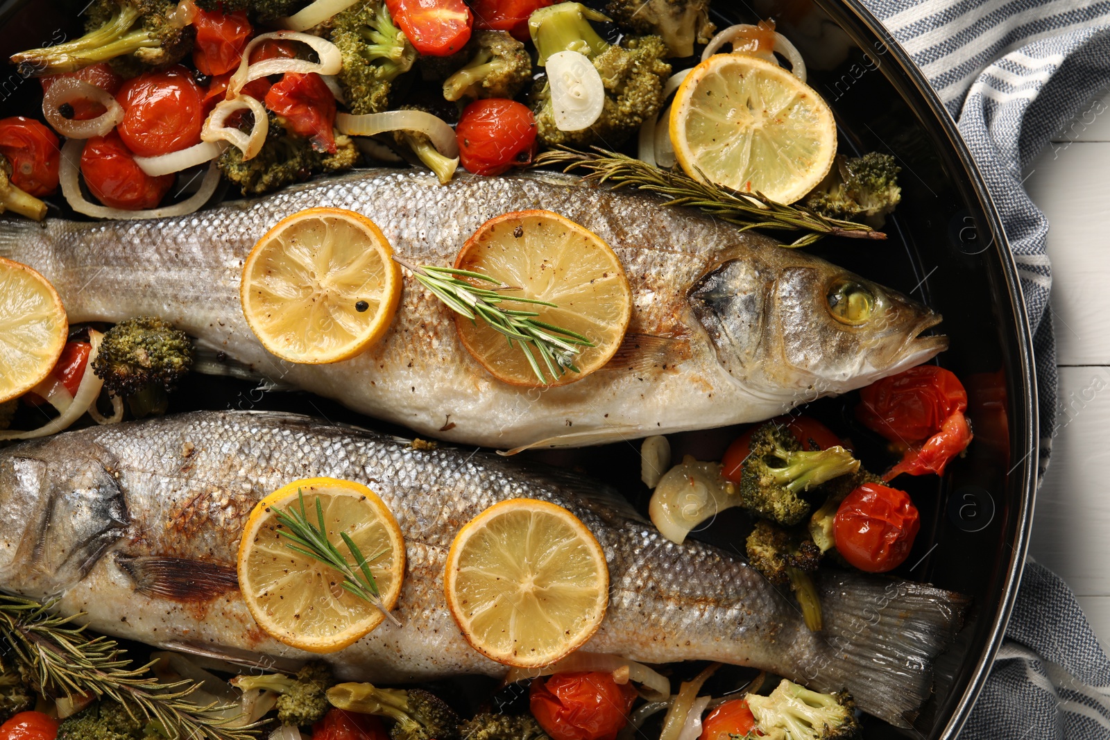 Photo of Baked fish with vegetables, rosemary and lemon on white wooden table, top view