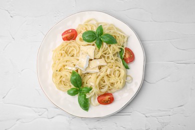 Delicious pasta with brie cheese, tomatoes and basil leaves on white textured table, top view