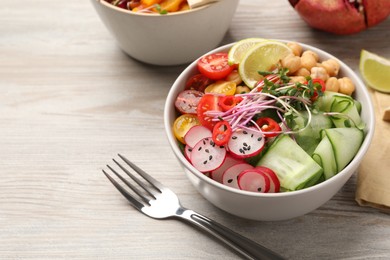 Photo of Bowl with many different vegetables on white wooden table. Vegan diet