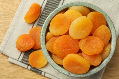 Photo of Bowl of tasty apricots on wooden table, top view. Dried fruits