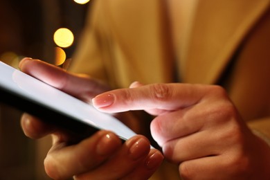 Woman using smartphone on blurred background, closeup