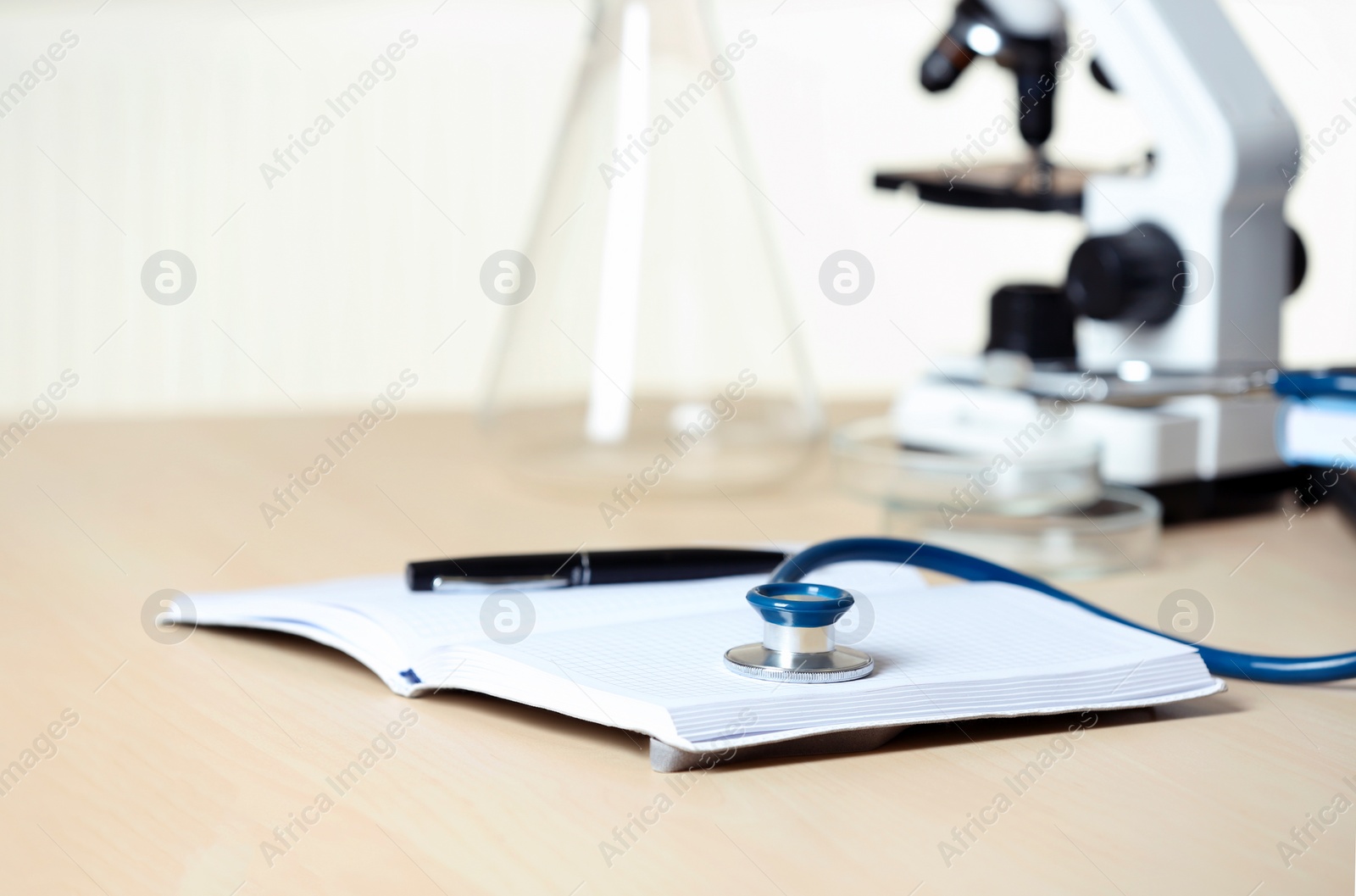 Photo of Stethoscope with notepad and pen on table. Medical students stuff