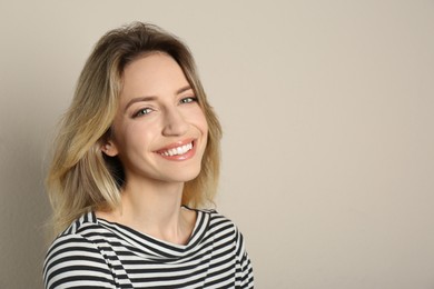 Portrait of happy young woman with beautiful blonde hair and charming smile on beige background. Space for text