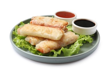 Photo of Delicious fried spring rolls and sauces isolated on white