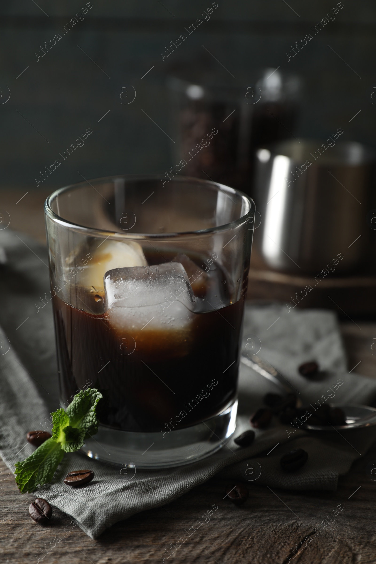 Photo of Glass of delicious iced coffee, mint and beans on wooden table