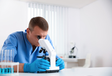 Photo of Scientist using modern microscope at table. Medical research