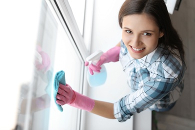 Young woman cleaning window glass at home