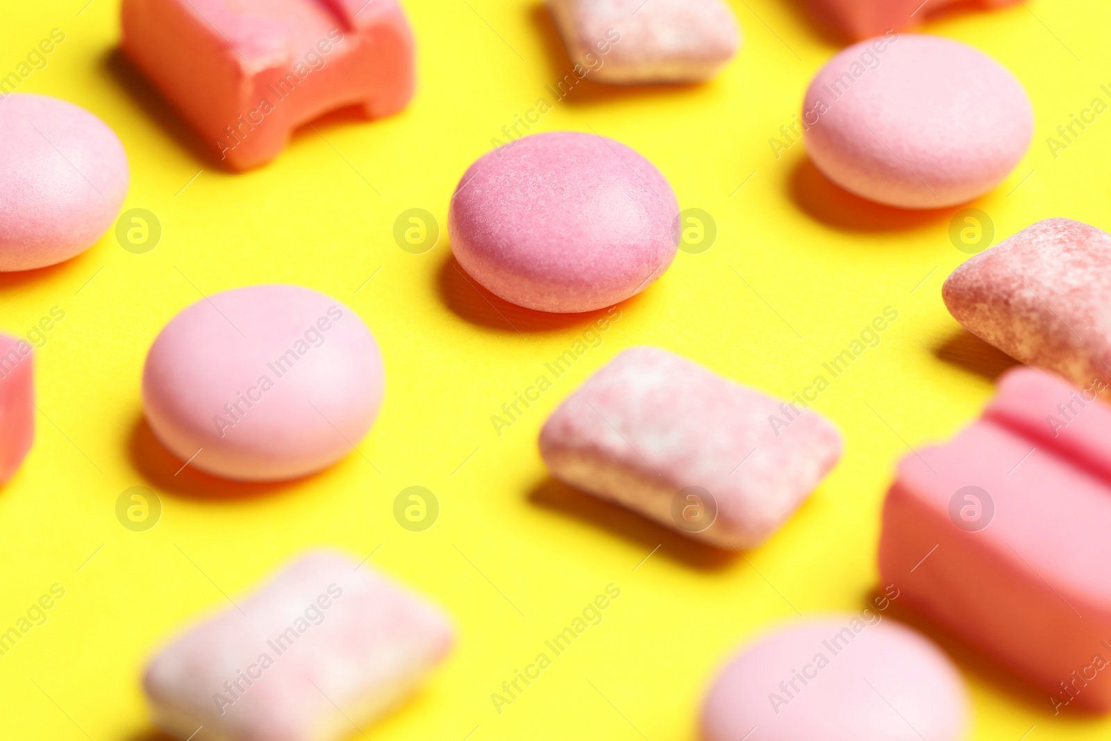 Photo of Pink bubble gums on yellow background, closeup